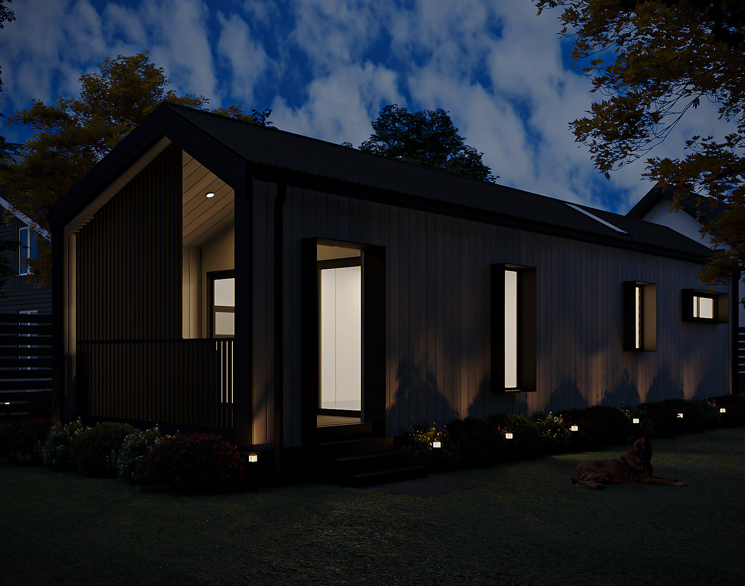 Side elevation view showing vertical cladding, window frames, dark gabled metal roof, and garden shrubbery (Lexicon Half light grey vertical cladding with dark Basalt roof and trim, captured at twilight under warm architectural lighting).